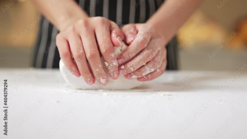 Female hands kneading dough in flour on the table Female hands kneading dough in flour on the table