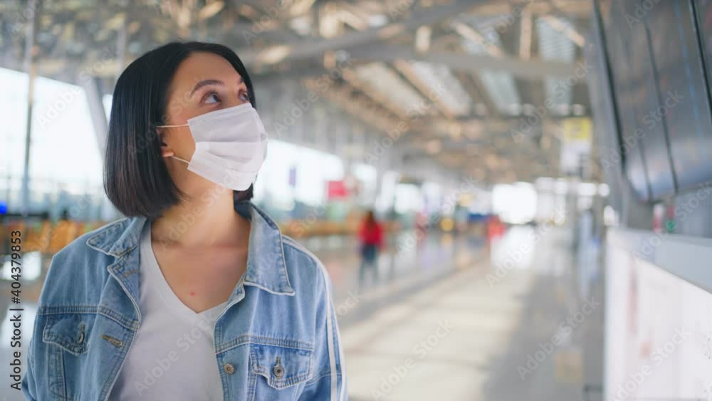 Girl traveler wearing face mask looking at time table to check flight Girl traveler wearing face mask looking at time table to check flight
