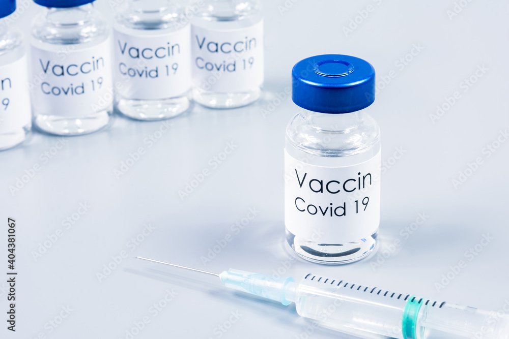 Flacons de vaccin Covid-19 et seringue sur table gris clair