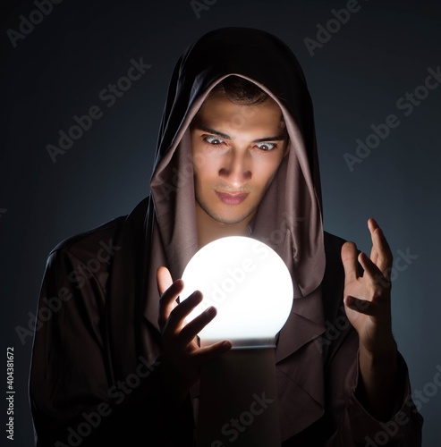 Принти на полотні Young wizard with crystal ball in dark room
