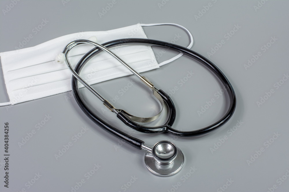 Stéthoscope et masque tissu blanc, sur table grise Stéthoscope et masque tissu blanc, sur table grise