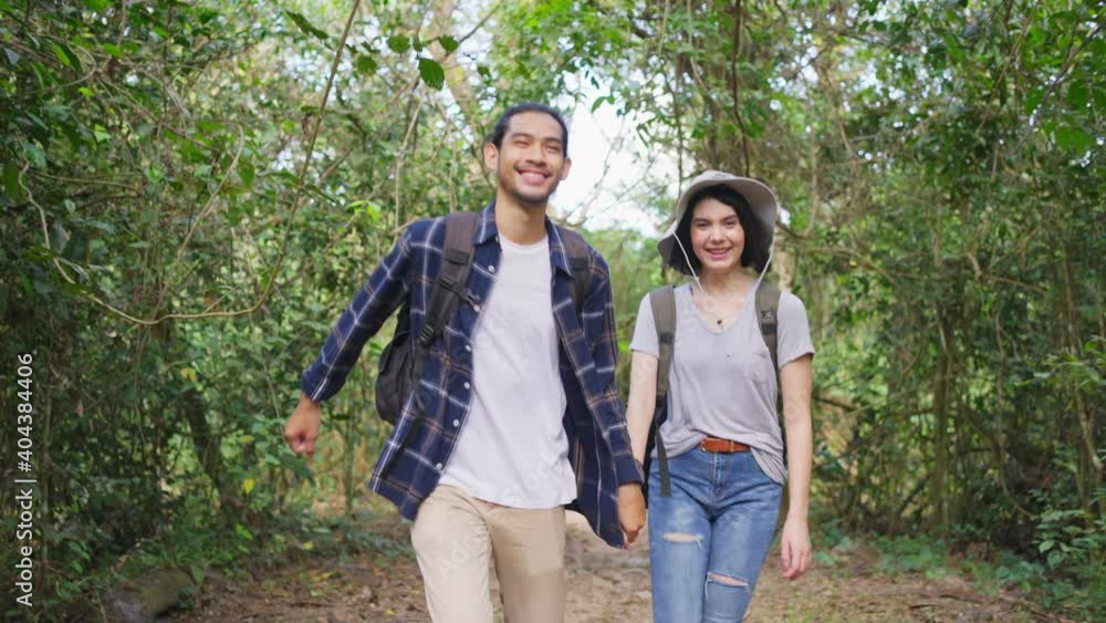 Young backpacker couple travel through a forest in the summertime. Young backpacker couple travel through a forest in the summertime.