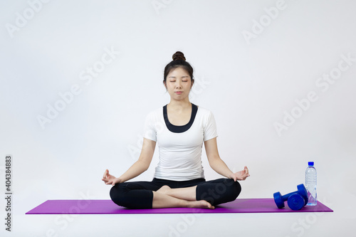 Asia woman sitting on yoga mat in lotus position on white background 