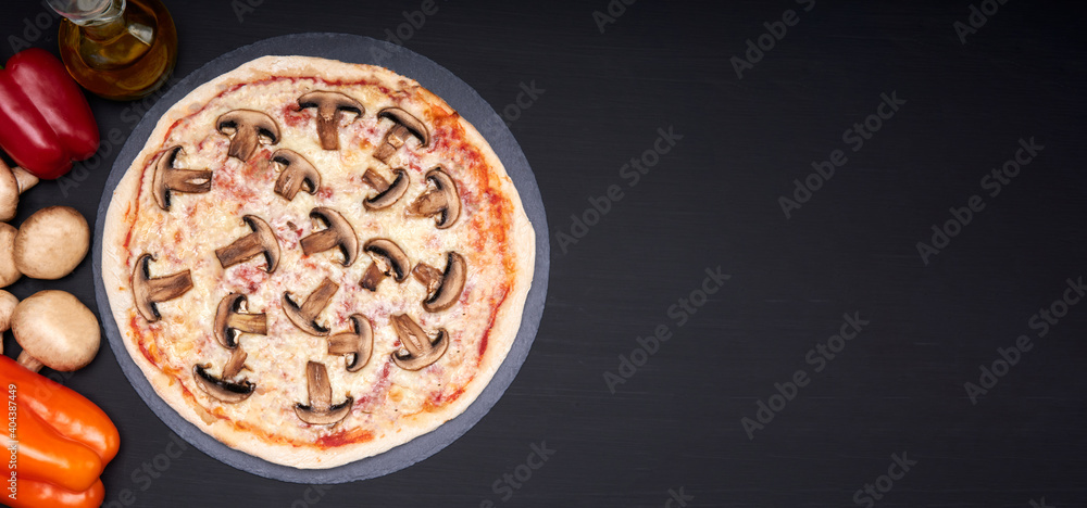 mushroom pizza, tomato sauce and mozzarella cheese on a stone plate with a black background with copy space for advertising. The pizza is accompanied by its main ingredients. mushroom pizza, tomato sauce and mozzarella cheese on a stone plate with a black background with copy space for advertising. The pizza is accompanied by its main ingredients.