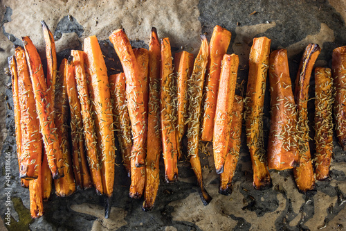 Sliced carrots on baking paper with sea salt, olive oil and rosemary.