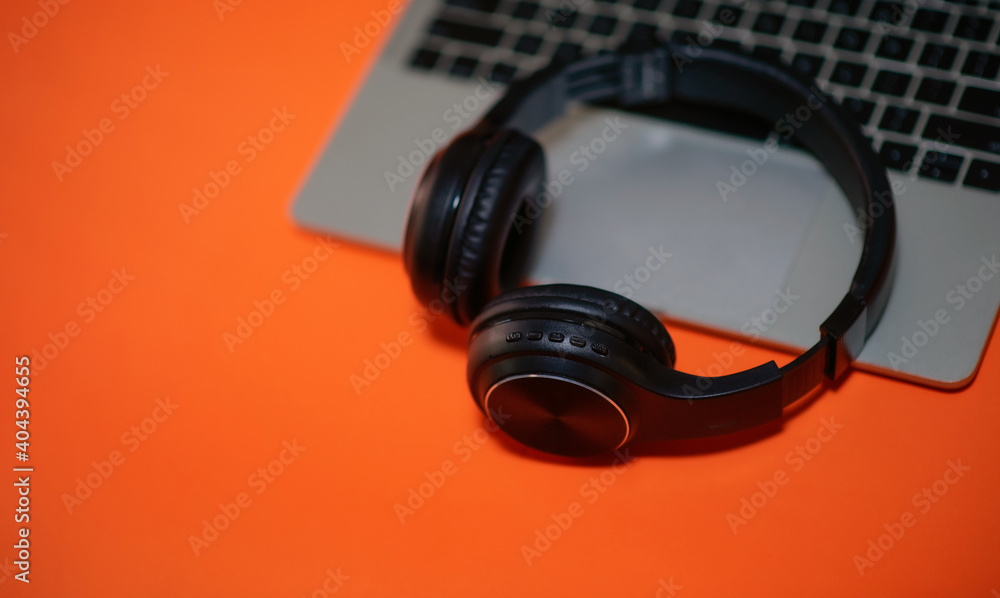 Black headphones on colored background, laptop, music concept Black headphones on colored background, laptop, music concept