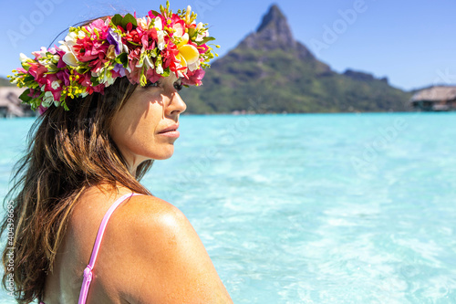 Woman wearing colorful flower crown on vacation at beautiful tropical island Bora Bora in French Polynesia