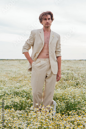 Tall handsome man standing on the chair in camomile flowers field