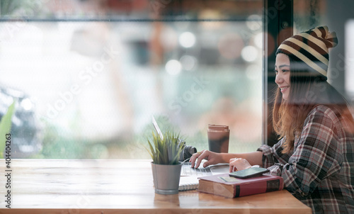 Portrait of young hipster female wearing wool hat working at co-workspace with happiness.