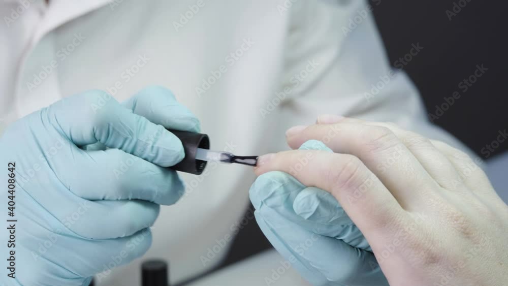 Master is covering the customer's nails with clear nail polish. Concept of the process of creating a manicure in a beauty salon. Closeup Master is covering the customer's nails with clear nail polish. Concept of the process of creating a manicure in a beauty salon. Closeup