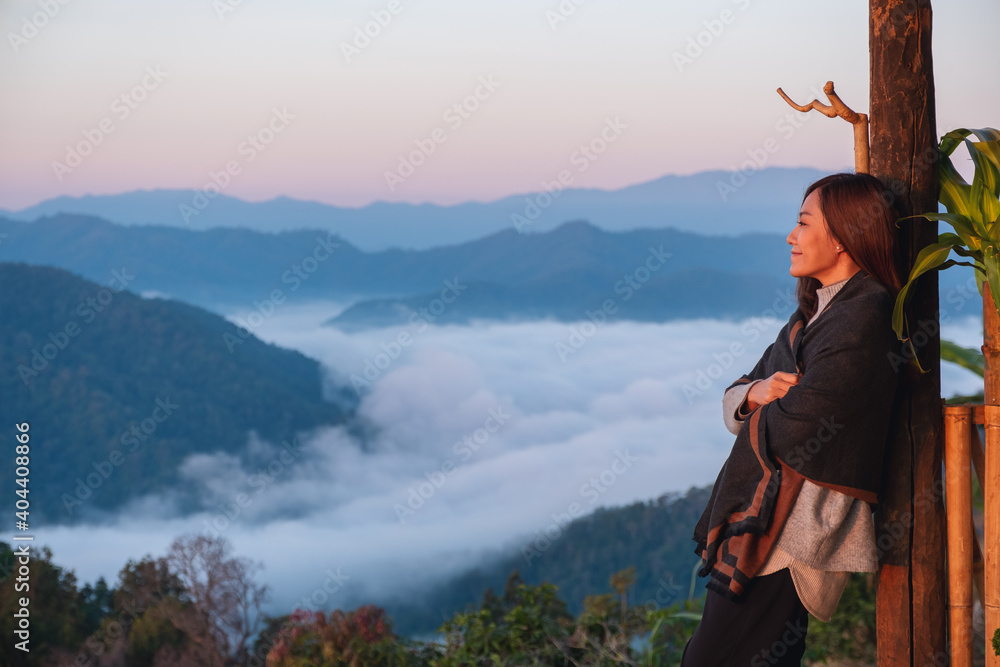 Αυτοκόλλητο A female traveler standing on wooden balcony, looking at a beautiful mountain an