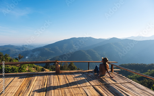 A female traveler sitting on wooden balcony and looking at a beautiful mountain view