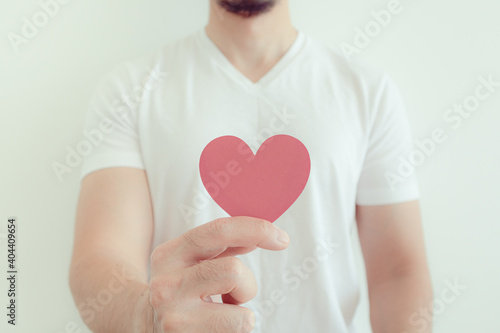 Fototapeta Naklejka Na Ścianę i Meble -  Man in white t-shirt shows pink heart shape in concept of love and Valentine.