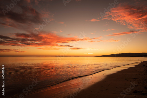 Gorgeous dawn at seashore, sky colors reflecting on bright sea surface, yellow horizon. Iriomote Island, natural world heritage.