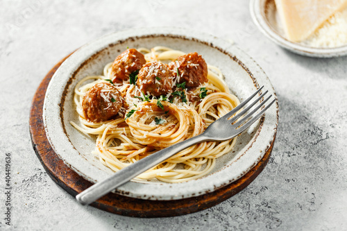 Spaghetti with meatballs and tomato sauce served with herbs and Parmesan.