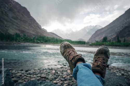 Traveler resting on a mountain plateau. POV view, legs close up on the background of mountain landscape