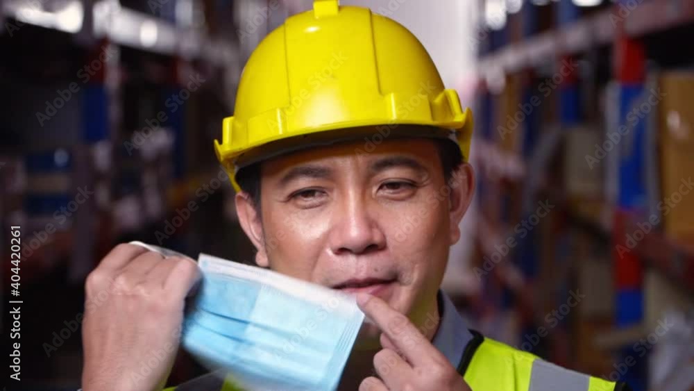 Asian male factory engineer worker with safety helmet taking off face mask and smile. Protection agianst coronavirus. Asian male factory engineer worker with safety helmet taking off face mask and smile. Protection agianst coronavirus.
