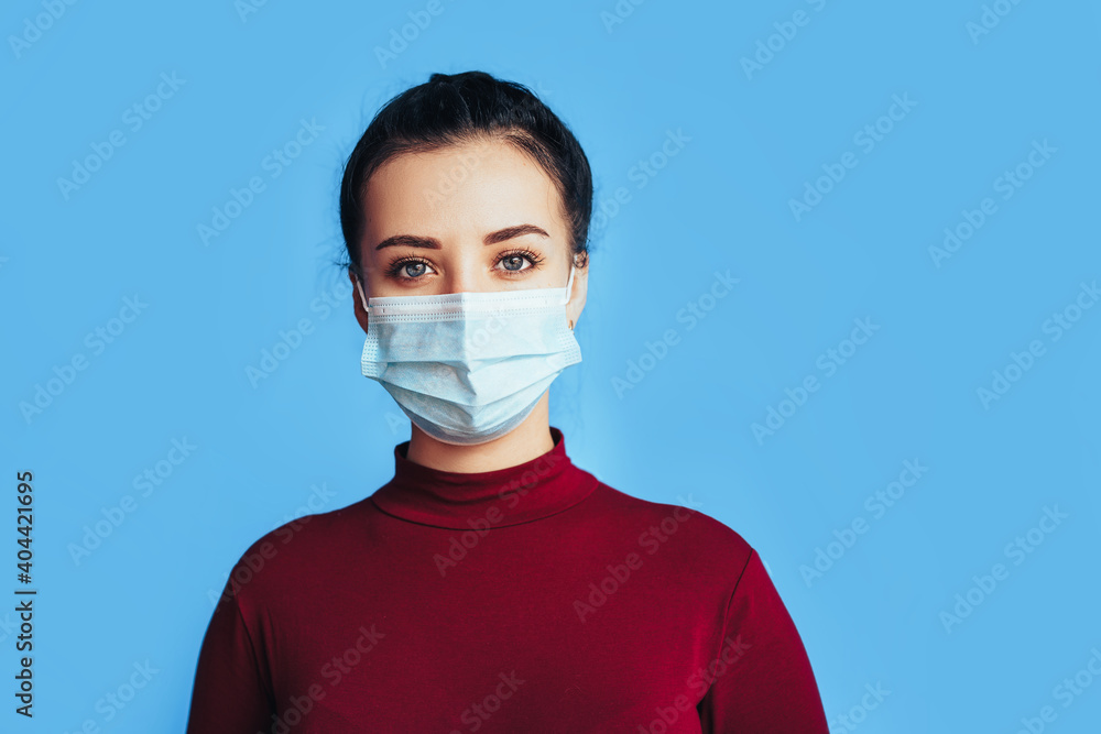 Woman in protective medical mask in front of a blue background. Health protection. Preventing disease during a pandemic Woman in protective medical mask in front of a blue background. Health protection. Preventing disease during a pandemic