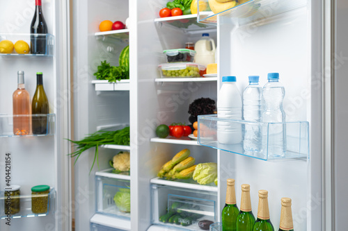 Open fridge full of fruits, vegetables and drinks