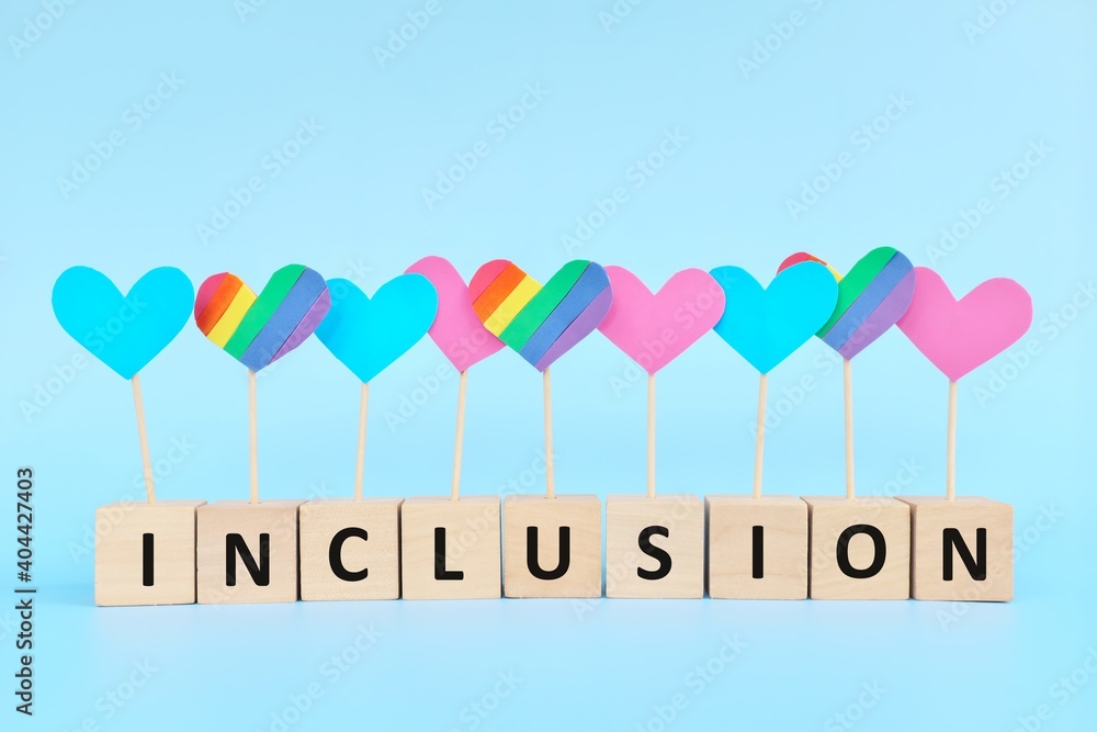 LGBT or LGBTQ gender equality, inclusion and diversity concept. Rainbow flag color among pink and blue colored heart shape in wooden blocks. LGBT or LGBTQ gender equality, inclusion and diversity concept. Rainbow flag color among pink and blue colored heart shape in wooden blocks.
