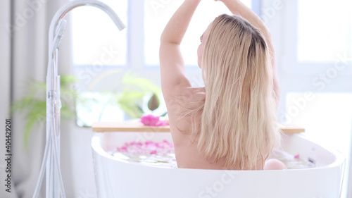 Fotografie Beautiful Caucasian Blonde Girl In Bikini Lying In Flower Bath In Resort Day Spa Salon