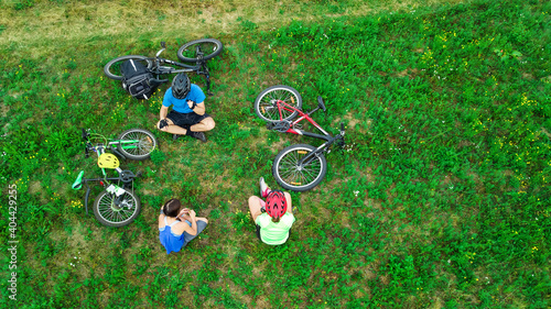 Family cycling on bikes aerial view from above, happy active parents with child have fun and relax on grass, family sport and fitness on weekend 