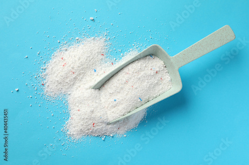 Plastic scoop with washing powder on blue background