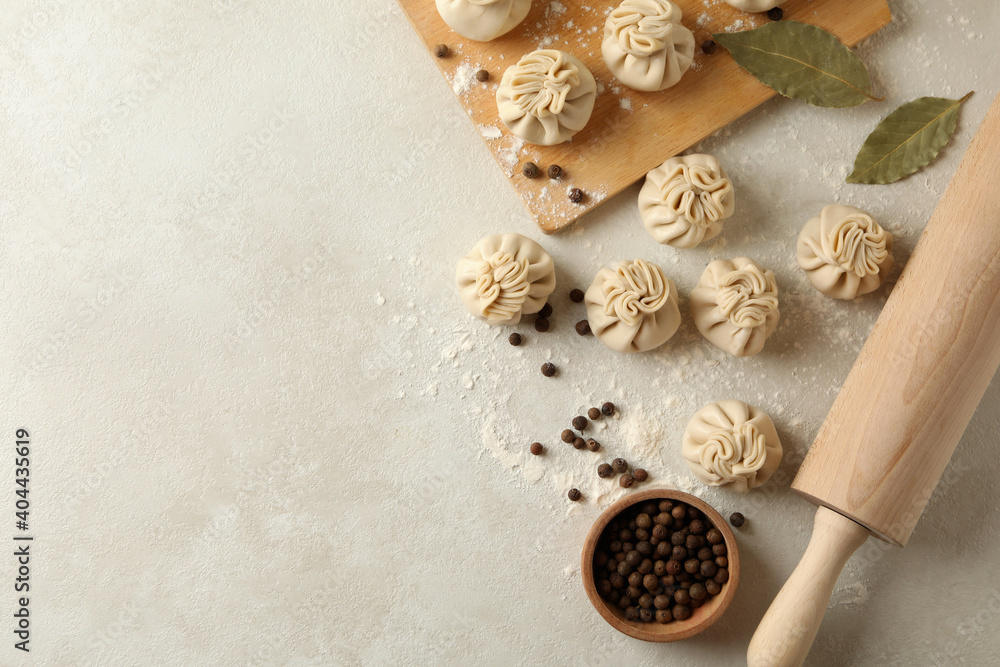 Concept of cooking with raw khinkali and spices on white textured background Concept of cooking with raw khinkali and spices on white textured background