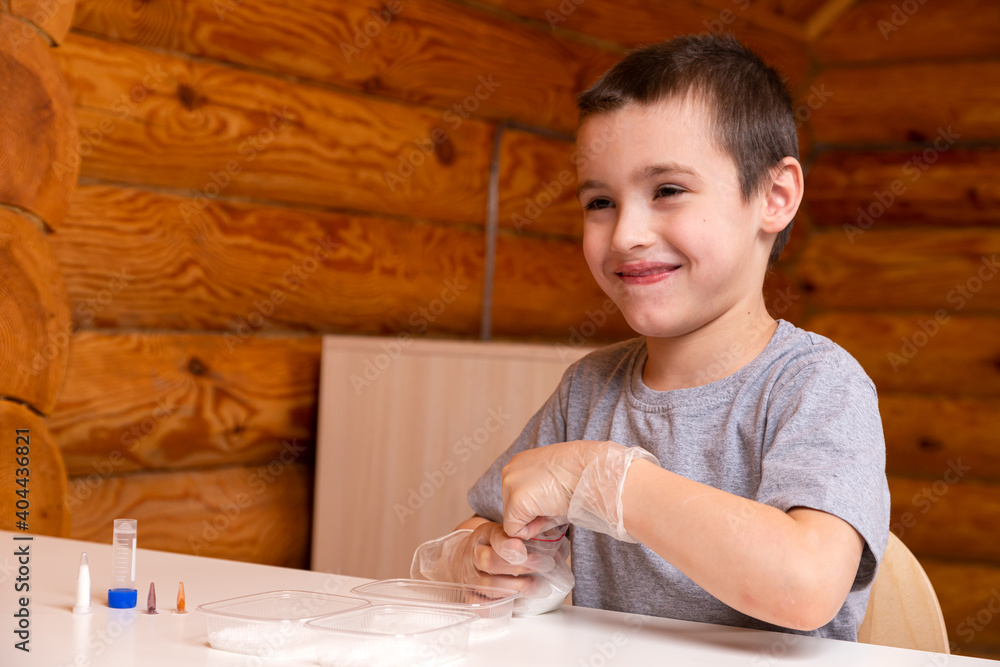 Chemistry education and training concept. Close-up - a boy pours a chemical element into a container; for experiments at home, there is a measuring spoon, a bag and a jar with a solution on the table. Chemistry education and training concept. Close-up - a boy pours a chemical element into a container; for experiments at home, there is a measuring spoon, a bag and a jar with a solution on the table.
