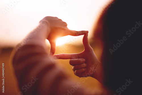 New year planning and vision concept, Close up of woman hands making frame gesture with sunset, Female capturing the sunrise. copy space. photo