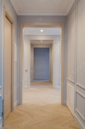 Modern and bright interior of empty cream colored corridor with herringbone parquet floor