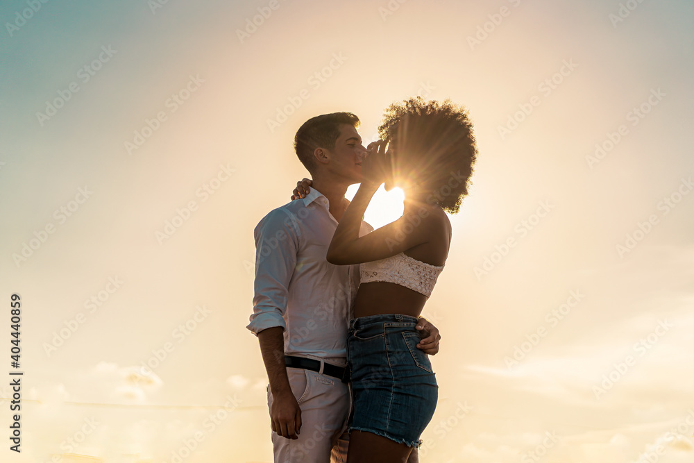 Φωτογραφία Couple of mixed race young people in live hugging and kissing outdoors