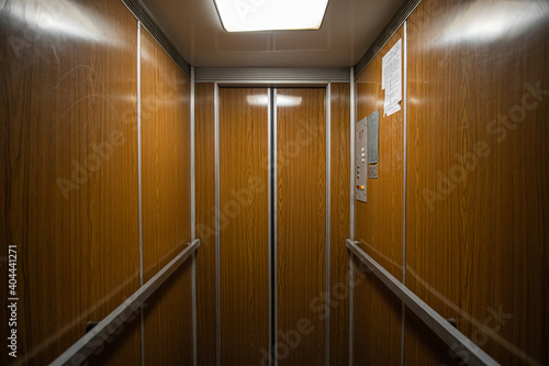 Interior inside a closed clean old Soviet elevator car lined with wood. photo