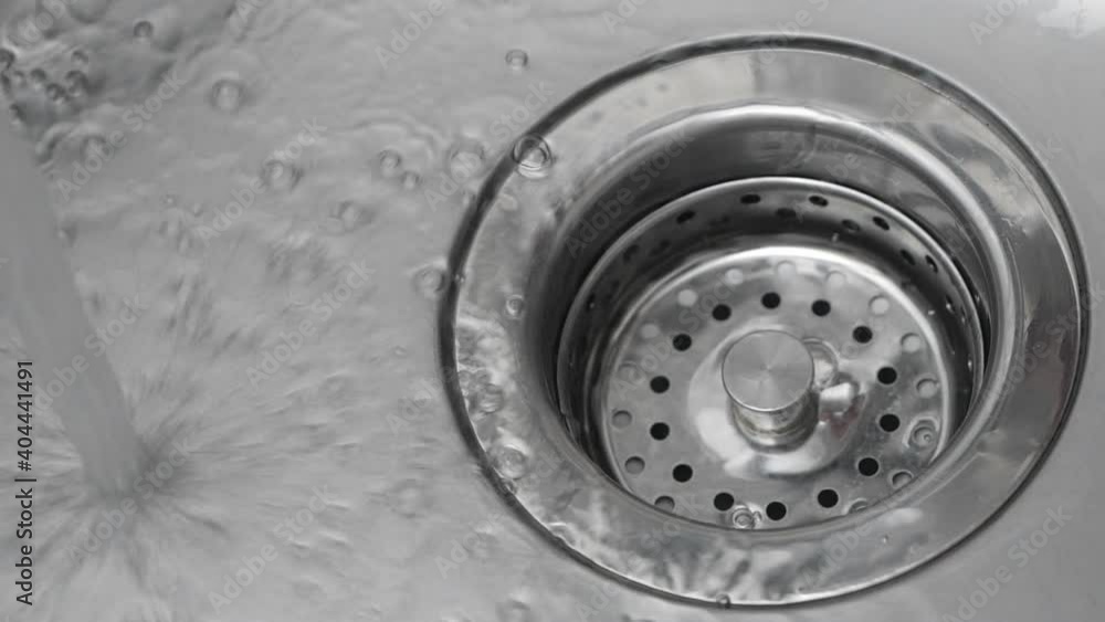 Streaming water in sink. Water stream going down the drain. Streaming water in sink. Water stream going down the drain.
