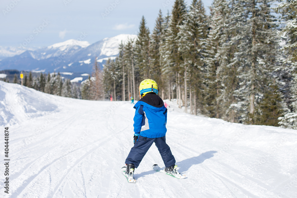 Cute little boy, skiing happily in Austrian ski resort in the mountains