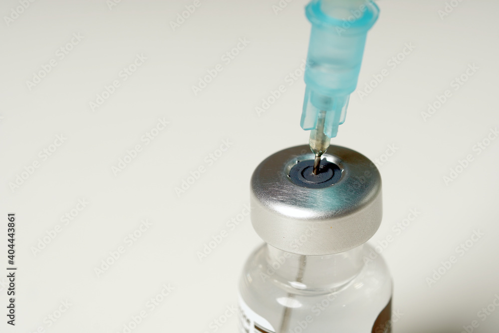 doctor hands injecting a syringe needle into a small bottle with a vaccine or drug assign virus or flu. doctor hands injecting a syringe needle into a small bottle with a vaccine or drug assign virus or flu.