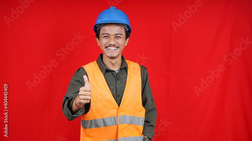 asian construction worker man wearing uniform, helmet with ok gesture isolated red background