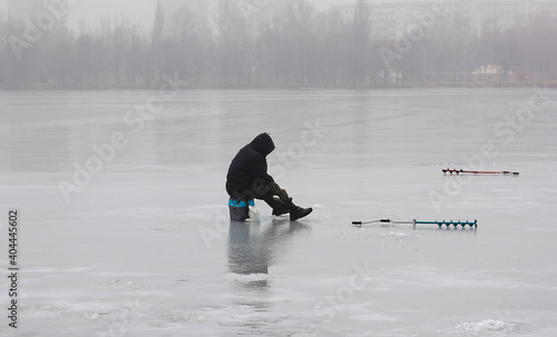 Fisherman in winter catches fish on ice near shore