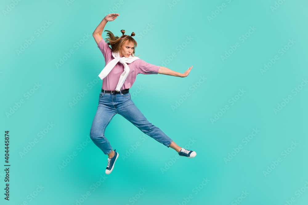 Full size profile side photo of young attractive beautiful serious girl jumping karate isolated on teal col or background