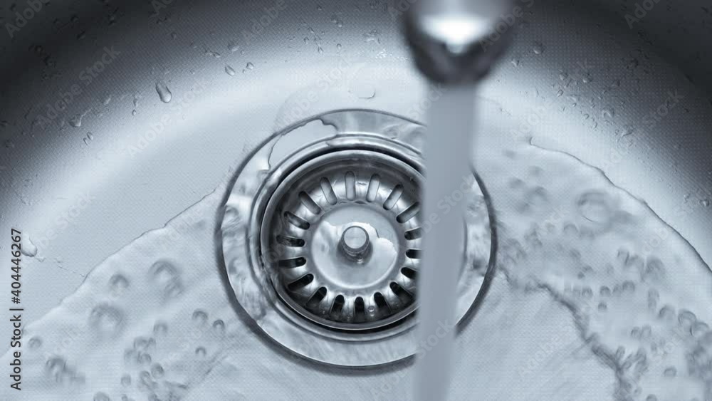 Streaming water in sink. Water stream going down the drain. Streaming water in sink. Water stream going down the drain.