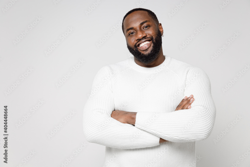 Handsome attractive smiling cheerful young african american man 20s wearing casual basic sweater standing holding hands crossed looking camera isolated on white color wall background studio portrait. Handsome attractive smiling cheerful young african american man 20s wearing casual basic sweater standing holding hands crossed looking camera isolated on white color wall background studio portrait.
