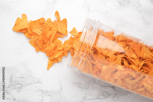 A jar of nachos drop and spill on the marble table.