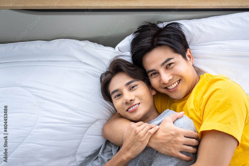 Happy Asian homosexual gay men male couple lying and embracing on bed. LGBT and sexual diversity concept. Looking at camera. Happy Asian homosexual gay men male couple lying and embracing on bed. LGBT and sexual diversity concept. Looking at camera.