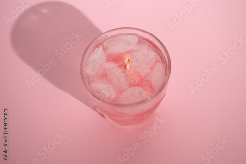 Pink drink with ice cubes. Drowning hand. Drunk in love. Valentine's day aesthetic.