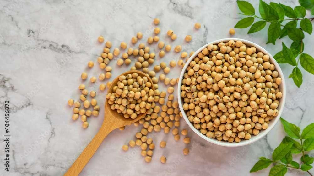 soybeans in white porcelain bowl with wooden spoon on the table. soybeans in white porcelain bowl with wooden spoon on the table.