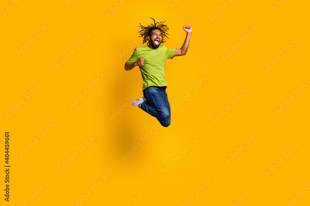 Photo portrait full body view of celebrating guy jumping up isolated on vivid yellow colored background Photo portrait full body view of celebrating guy jumping up isolated on vivid yellow colored background