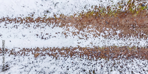 Billede på lærred panorama view from above on texture of snow covered gravel dirt road in the fore