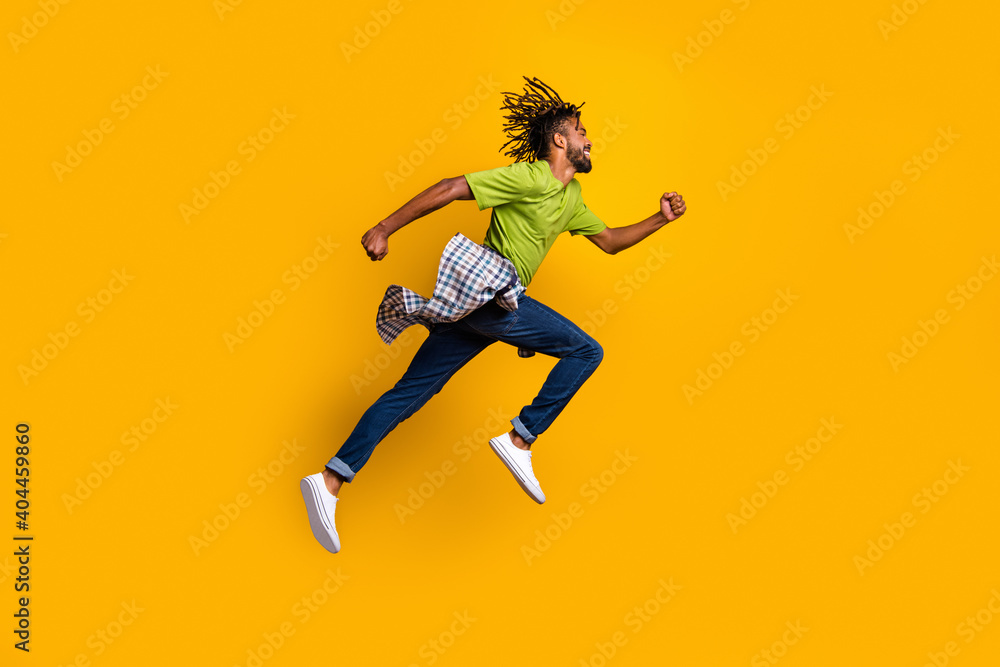 Photo portrait full body side view of man running jumping up isolated on vivid yellow colored background