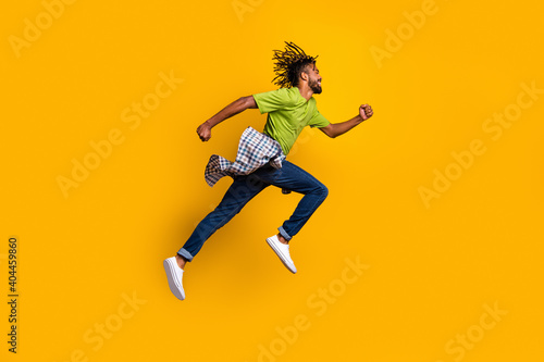 Photo portrait full body side view of man running jumping up isolated on vivid yellow colored background © deagreez