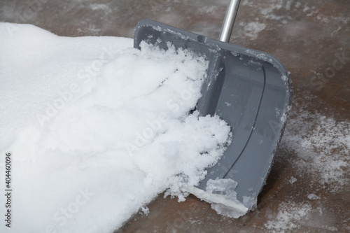 Snow removal. Grey plastic shovel cleans snow from yard